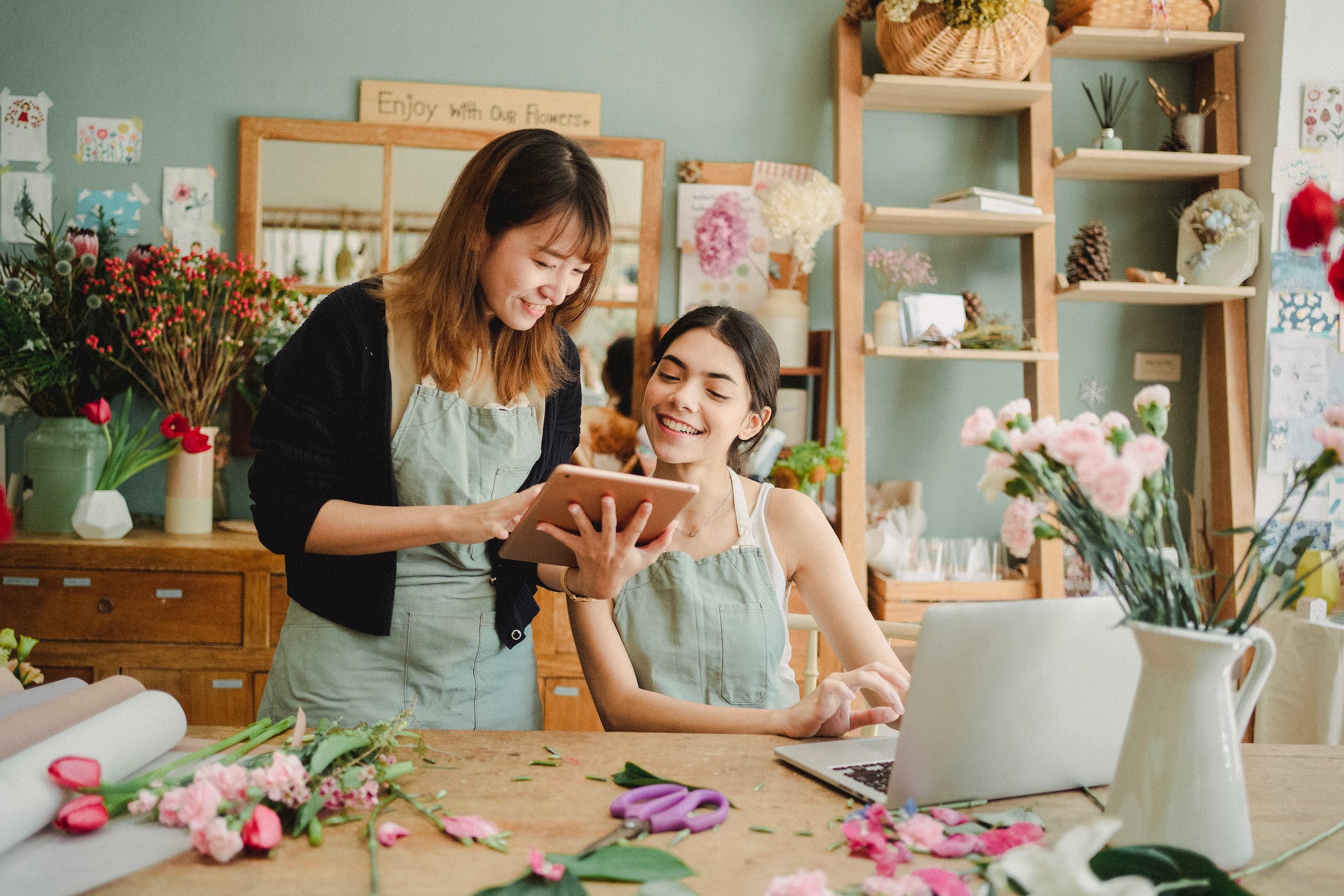 Two florist woman looking at a an tablet and smilling