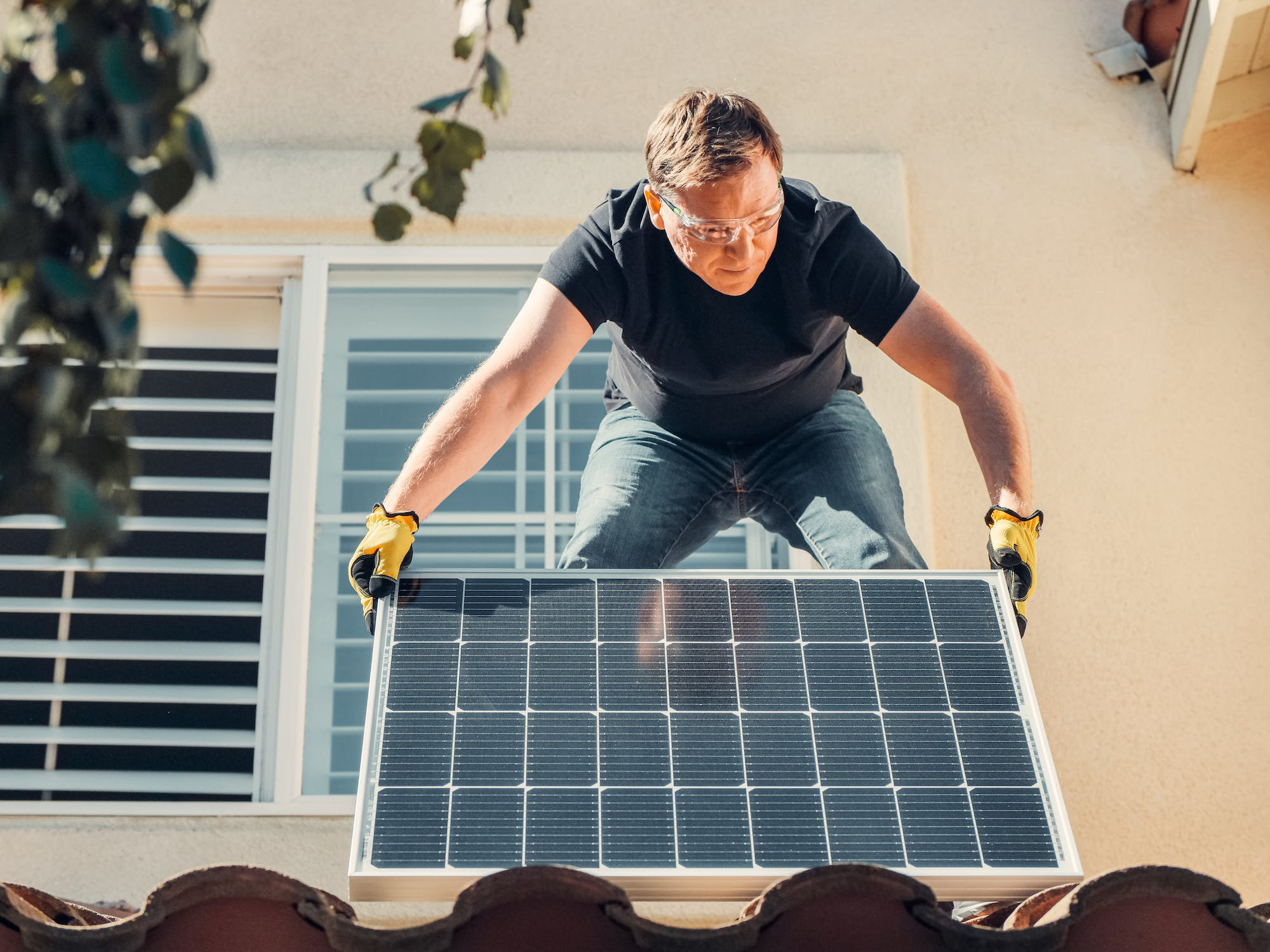 Man holding a solar panel on a roof