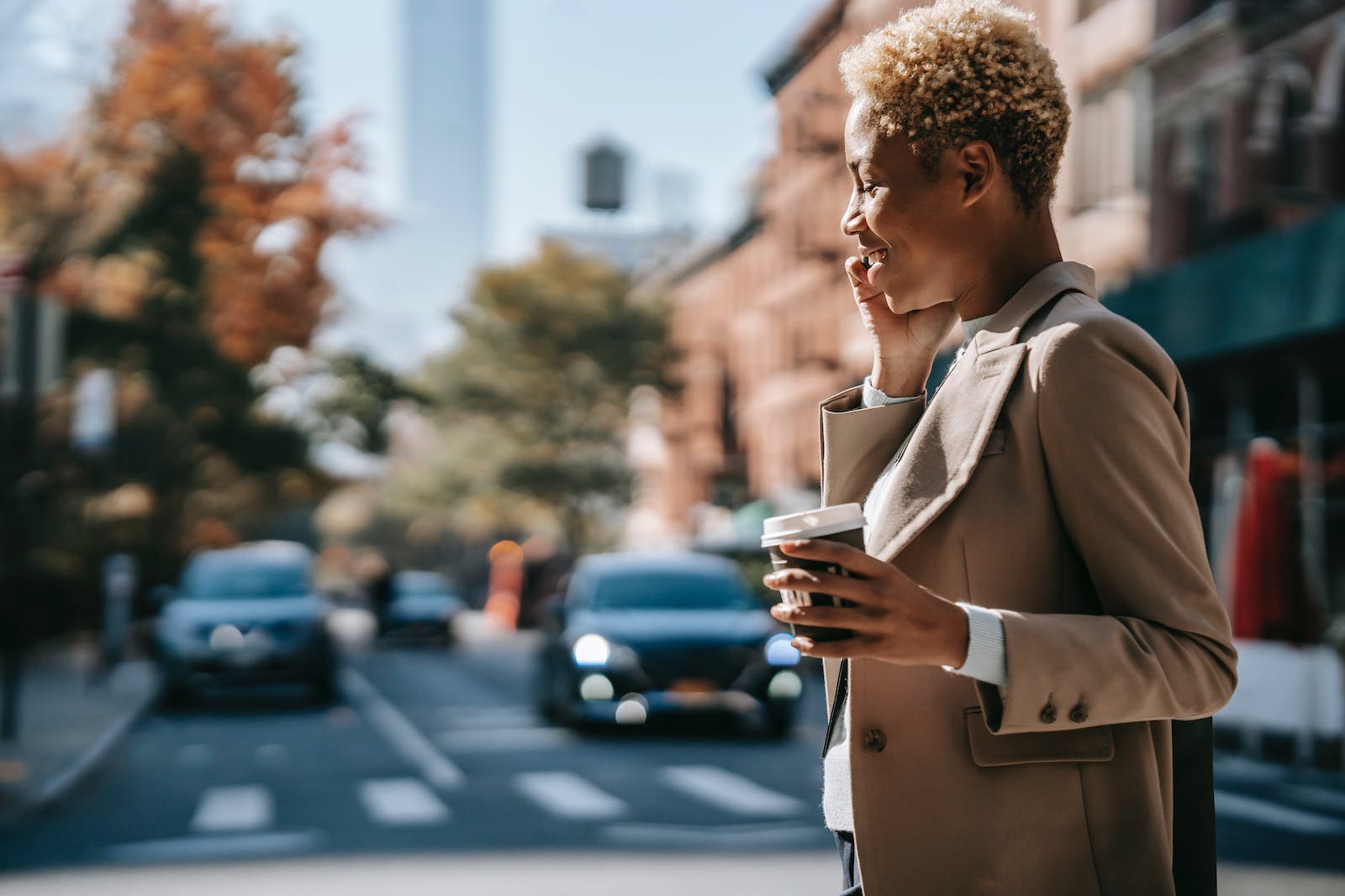 Woman crossing the road while talking on the phone and holding coffee in her hand